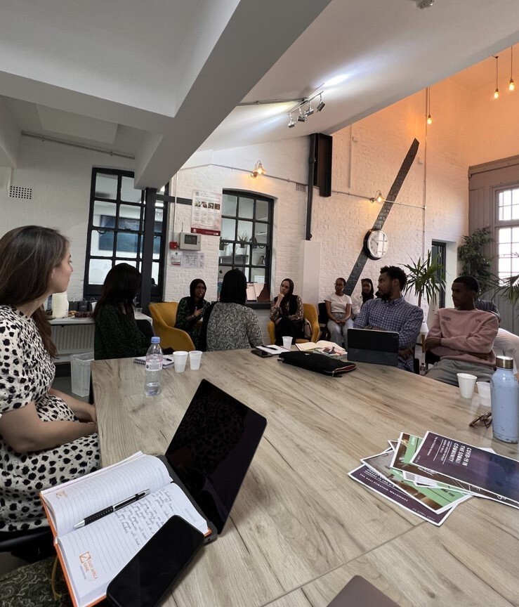 A group of people, sat around a large table taking part in a development workshop