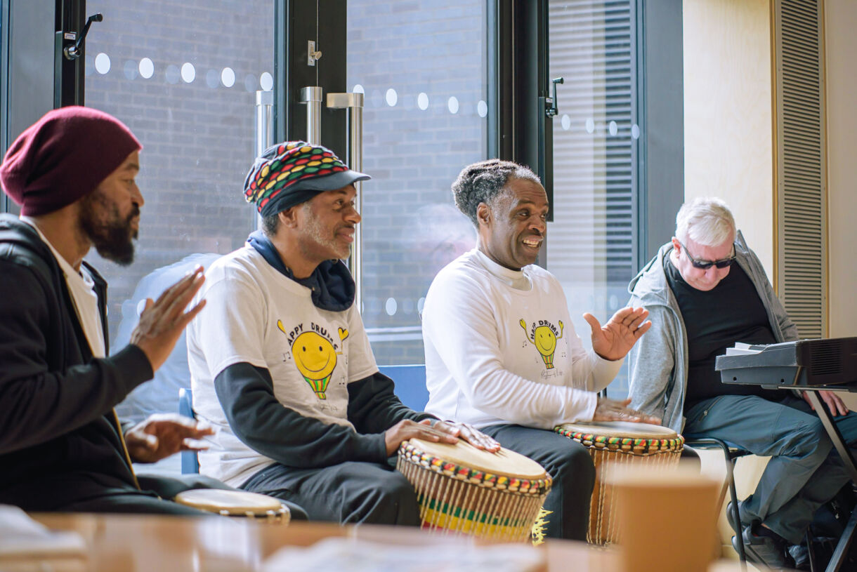 A group of men sitting together playing drums