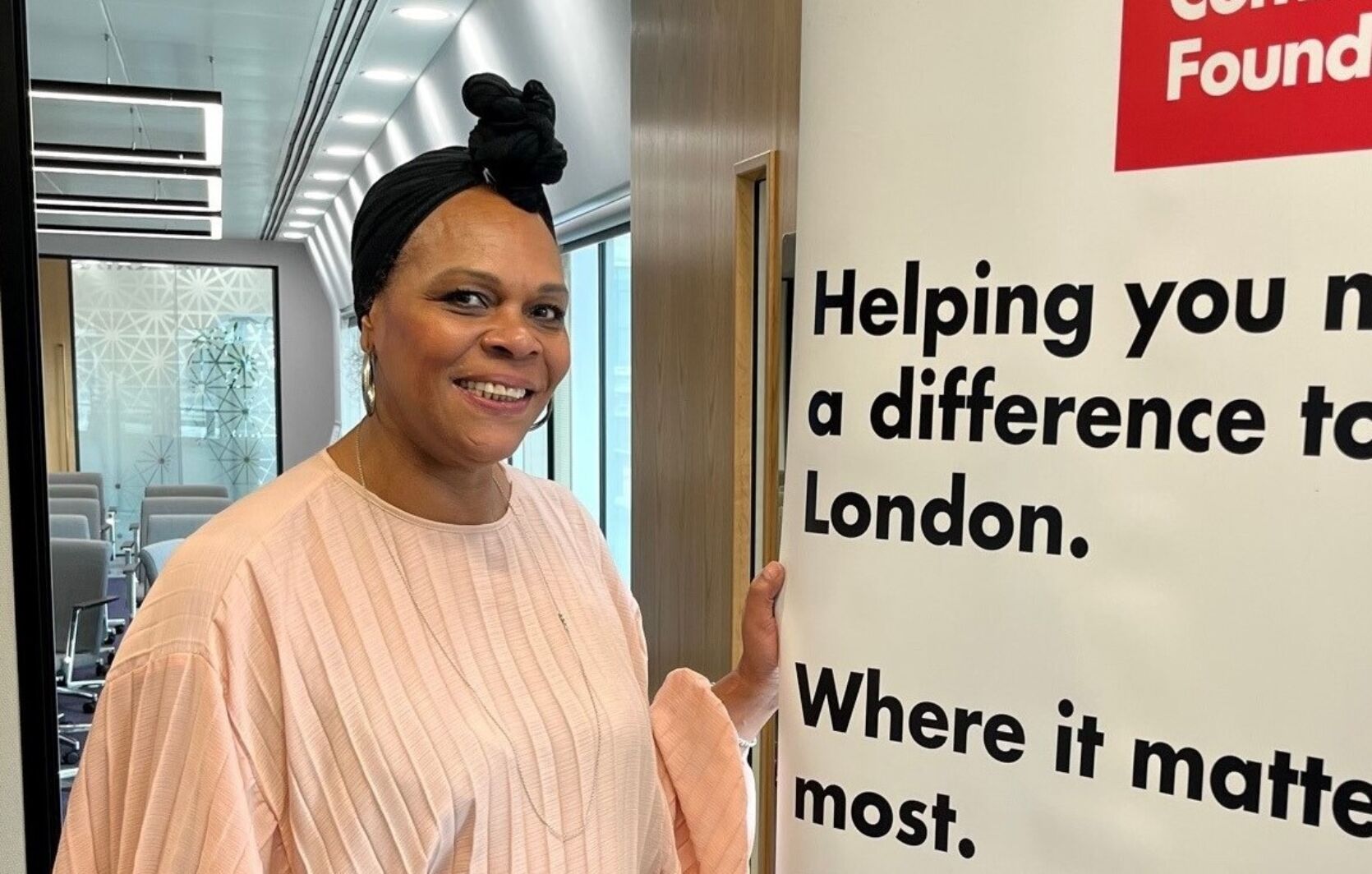 A person standing in front of a London Community Foundation banner - on the banner are the words 'Helping you make a difference to London. Where it matters most.'