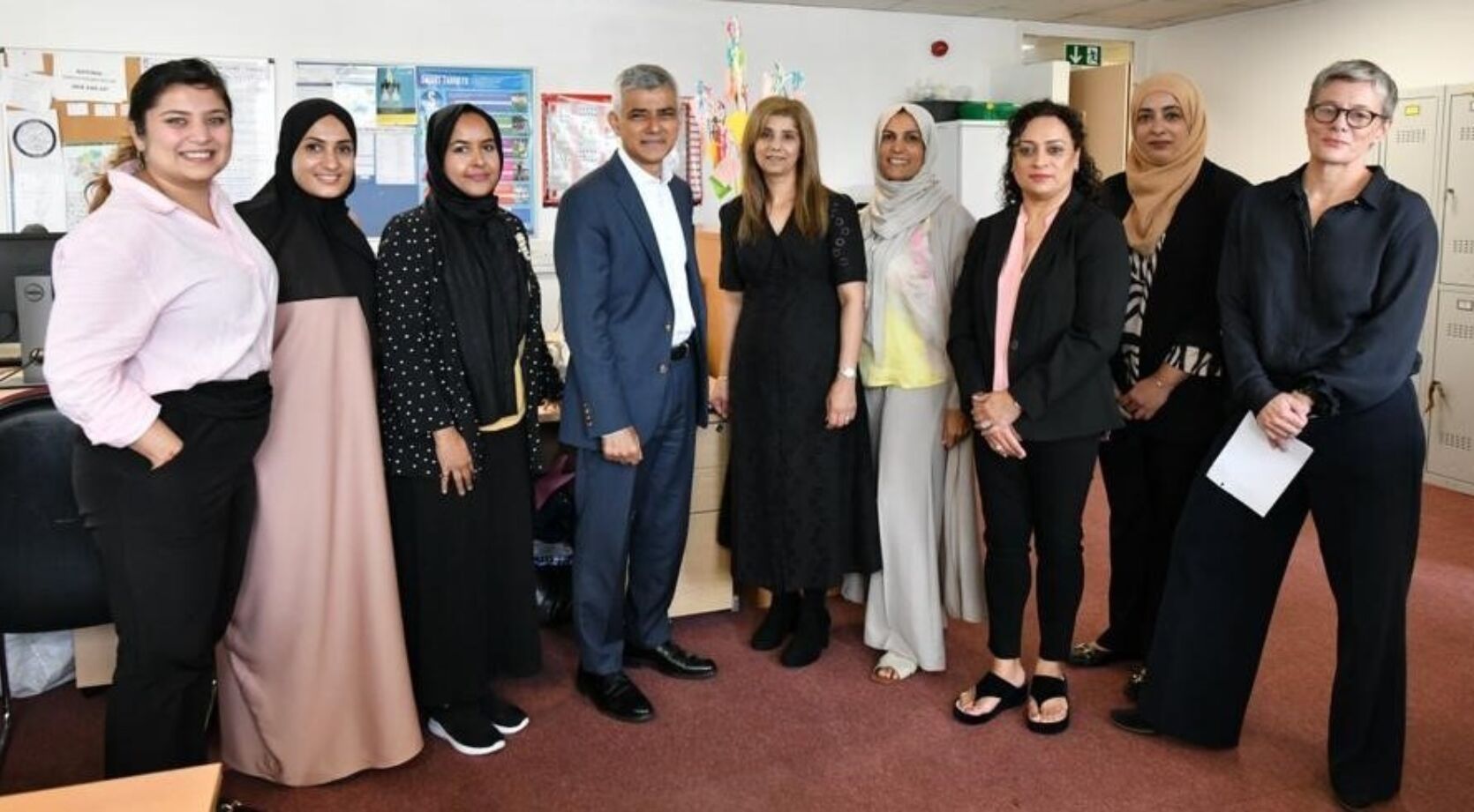 Members of the team from Kiran Support Services standing together in a line with the Mayor of London, Sadiq Khan, and The London Community Foundation CEO Kate Markey at their offices in Waltham Forest.